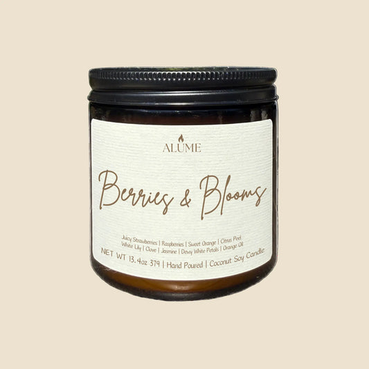 Candle jar labeled 'Berries & Blooms' by Alume on a white background